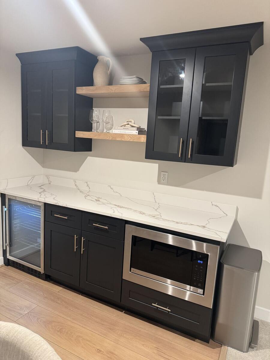 Black bar cabinets with floating oak shelves, beverage fridge and microwave