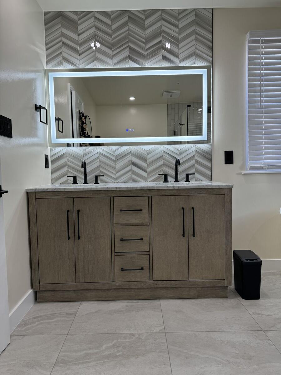 Double vanity with chevron marble backsplash and backlit mirror