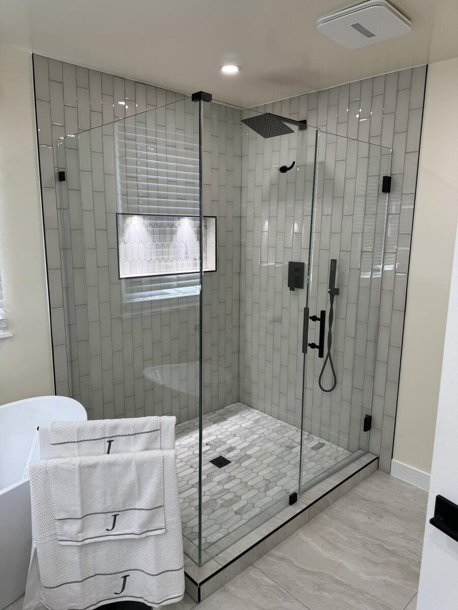 Frameless glass shower with white subway tile and matte black fixtures