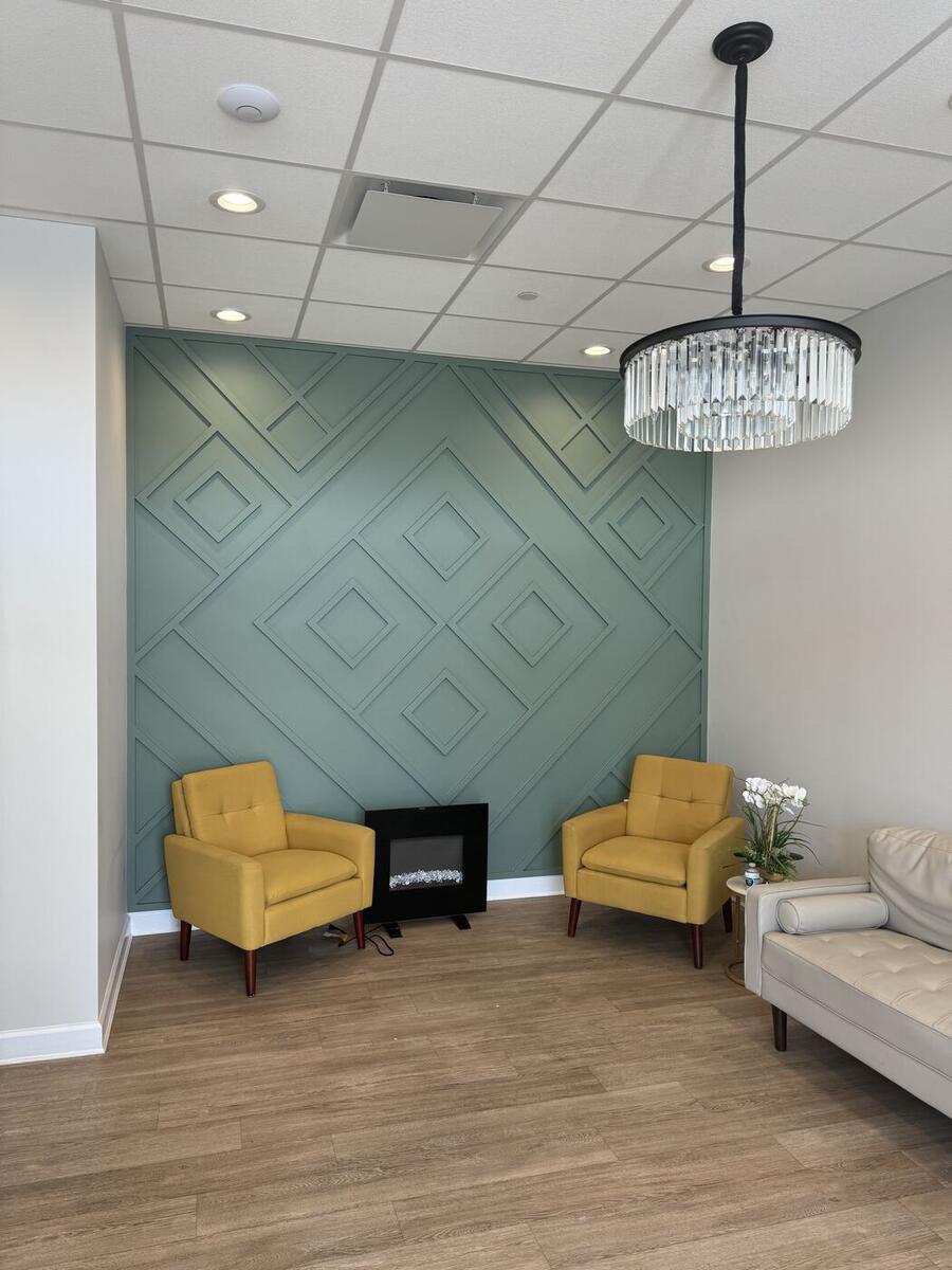 Office lounge with a green geometric accent wall and crystal chandelier