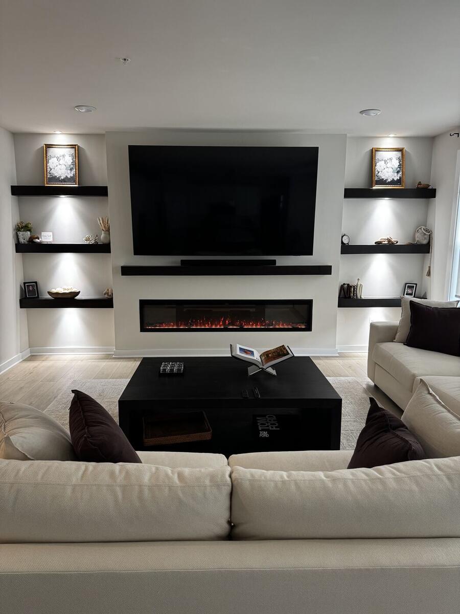 Recessed fireplace wall with TV and floating shelves in lit niches