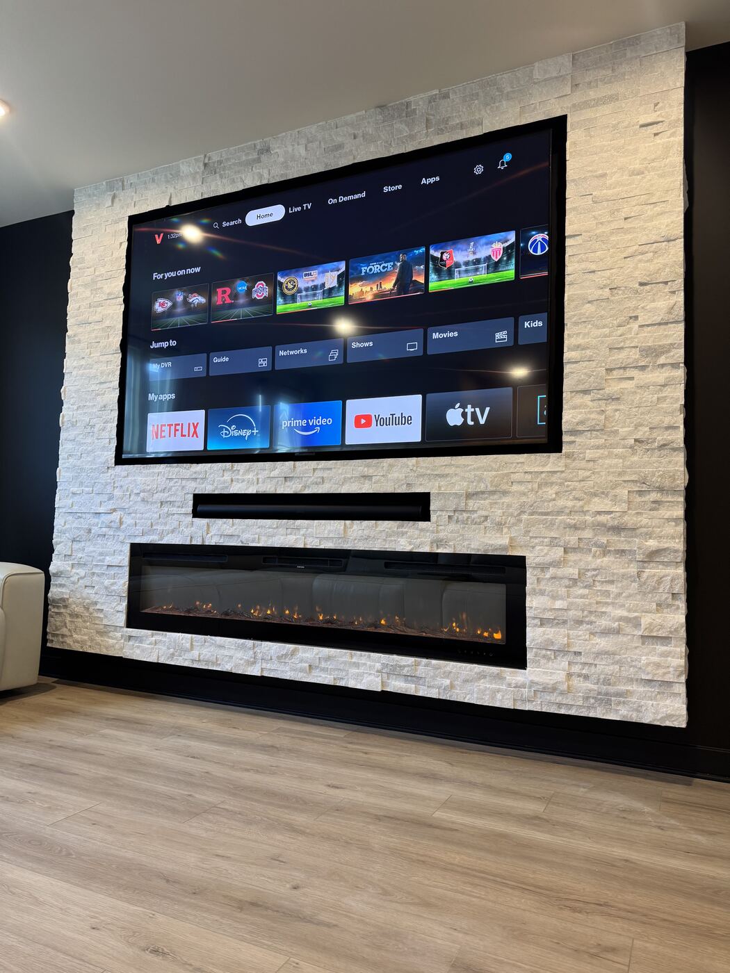 Straight-on view of the stone fireplace wall with TV and lit fireplace