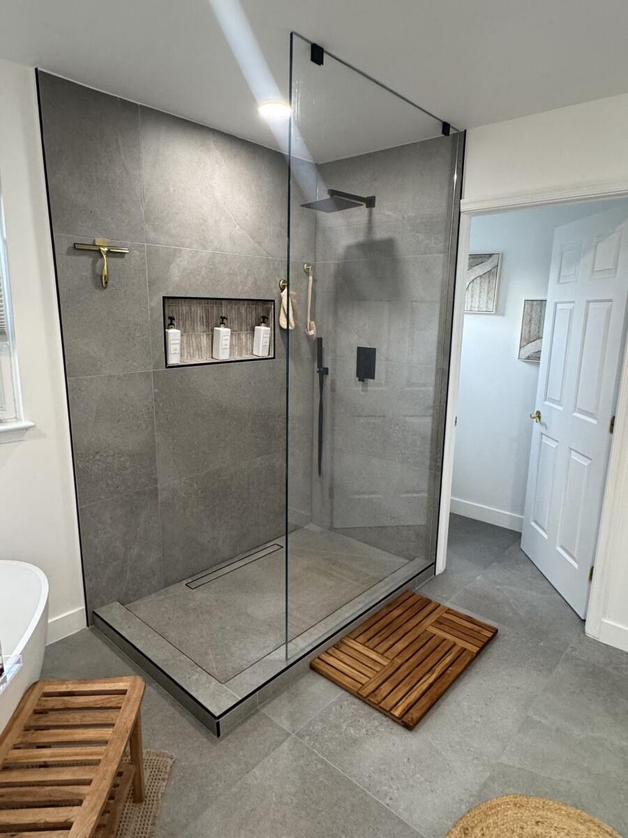 Walk-in shower with large-format grey tile and teak mat